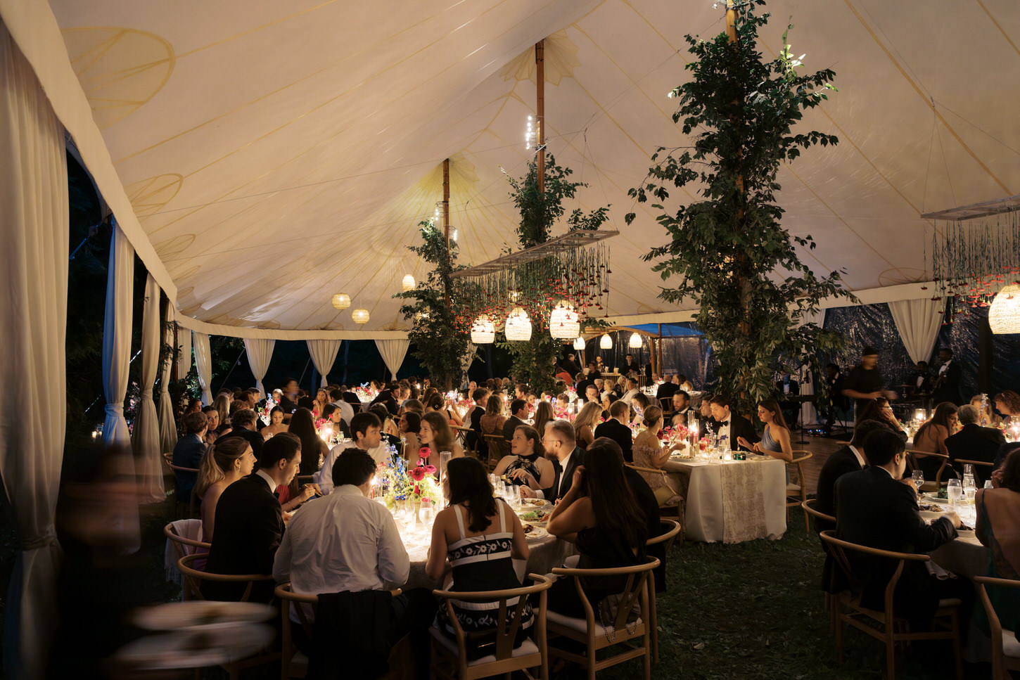 The wedding guests busily chat with each other while eating dinner in a beautiful tent set-up, an iconic wedding photography captured by Jenny Fu Studio.