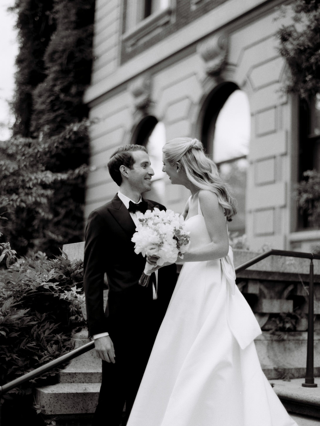 Black and white, candid image of the newlyweds with iconic building in the background, a digital and film wedding photography captured by Jenny Fu Studio.