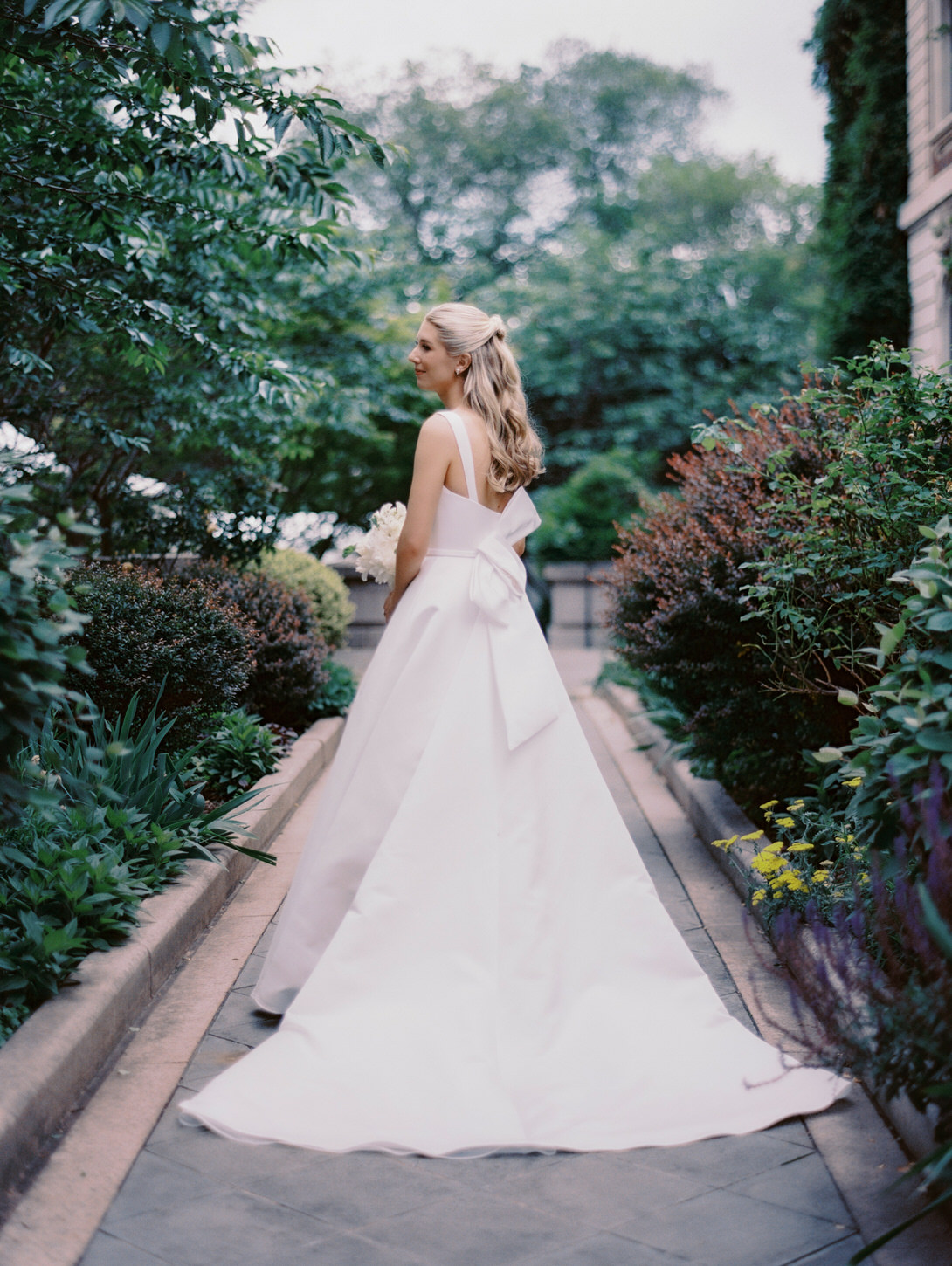 A portrait of the beautiful bride with lush greens in the background, a digital and film wedding photography captured by Jenny Fu Studio.