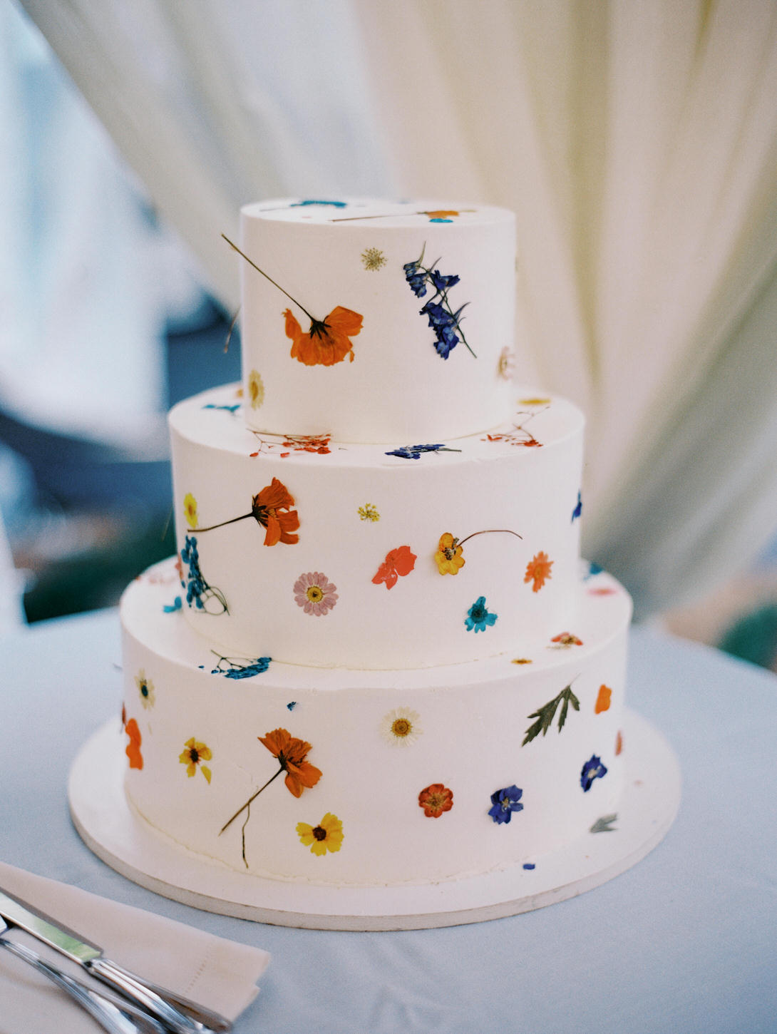 White wedding cake with bits of colorful flowers captured by Jenny Fu Studio.