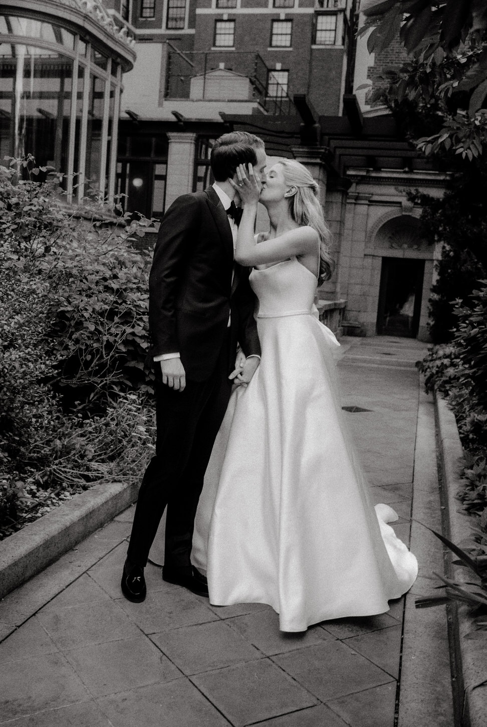 The newlyweds are lovingly kissing outdoors in the garden, a digital and film wedding photography captured by Jenny Fu Studio.