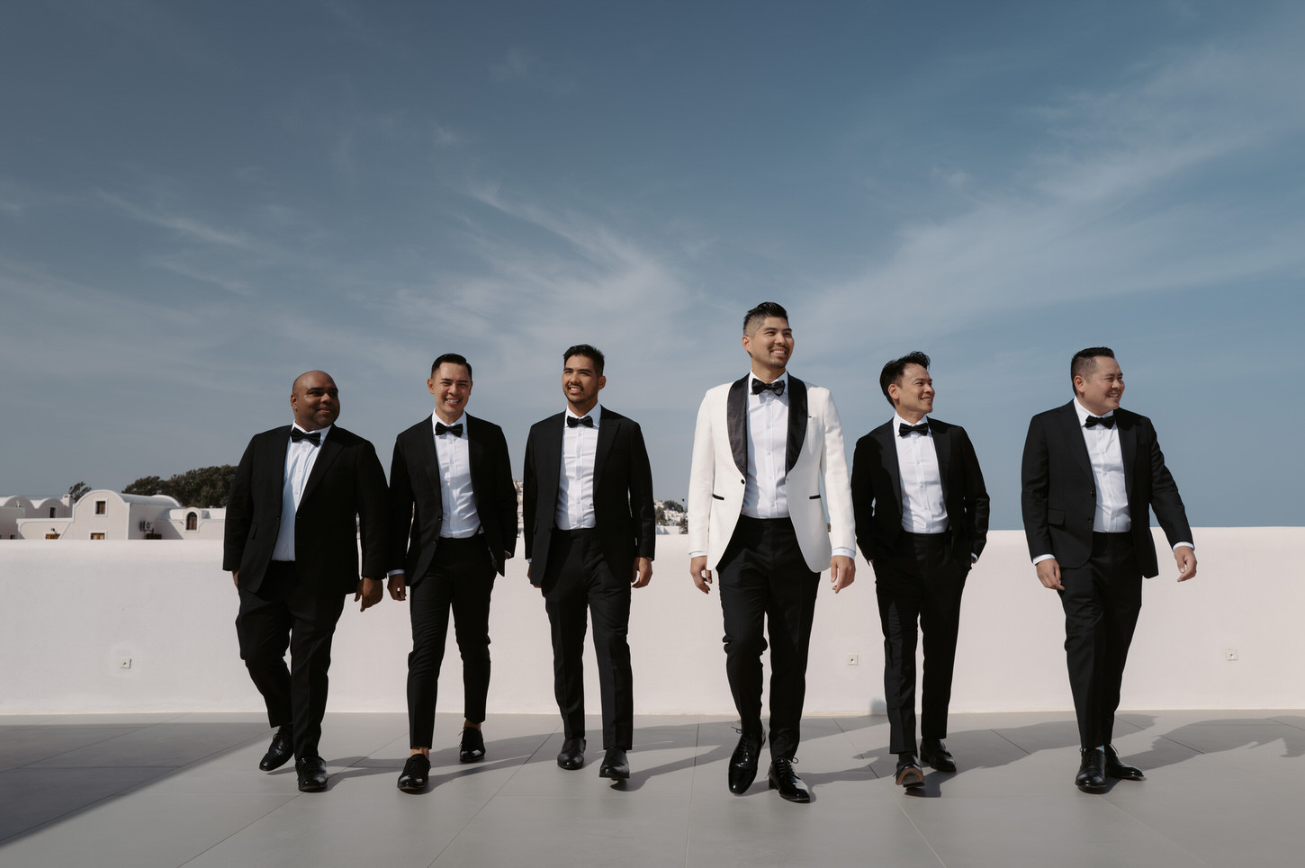 The groom and groomsmen looking their best in their suits at Santorini, Greece, captured by destination wedding photographer, Jenny Fu Studio.