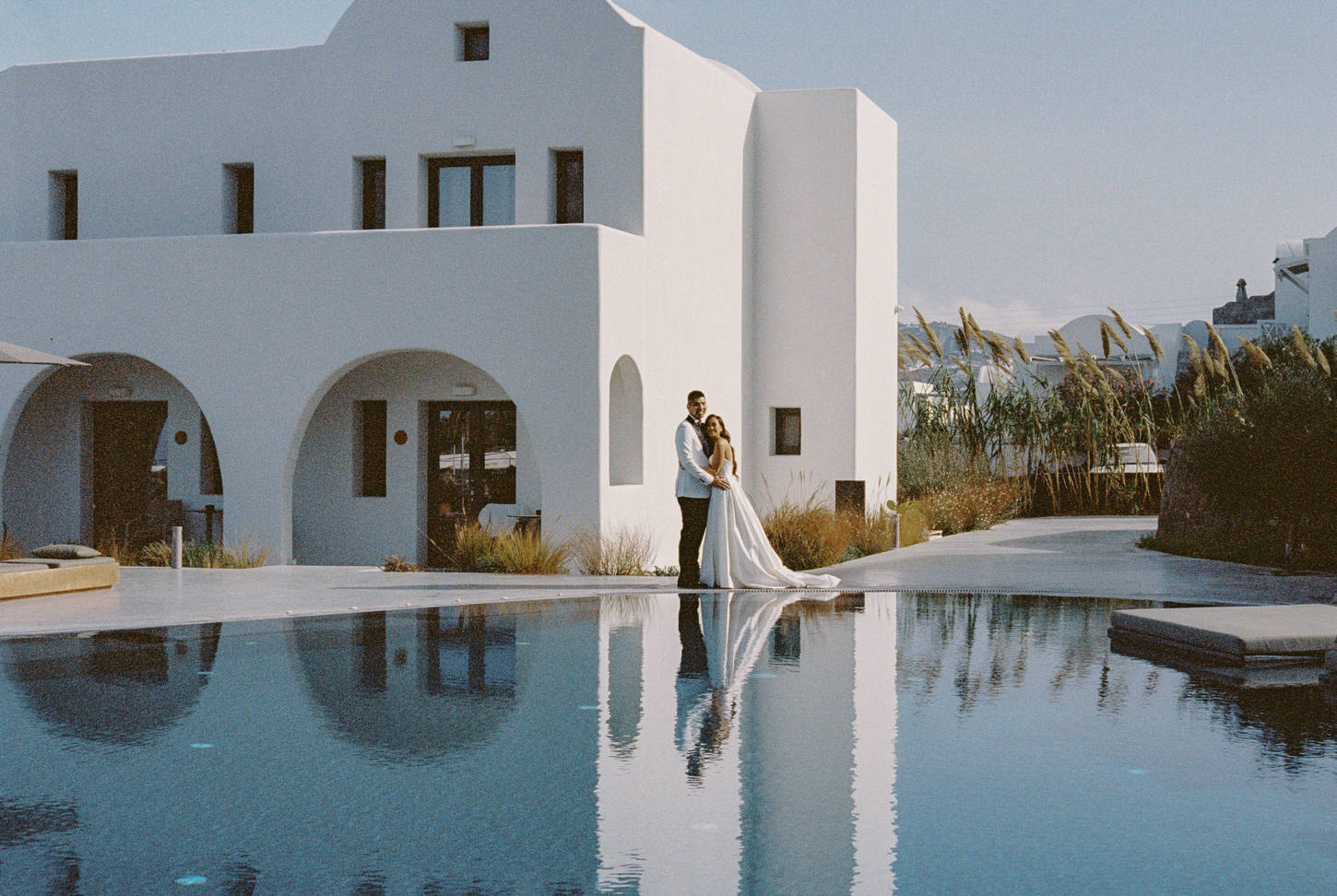 Poolside photo of the newlyweds with whitewashed villa in the background, captured by destination wedding photographer, Jenny Fu Studio.
