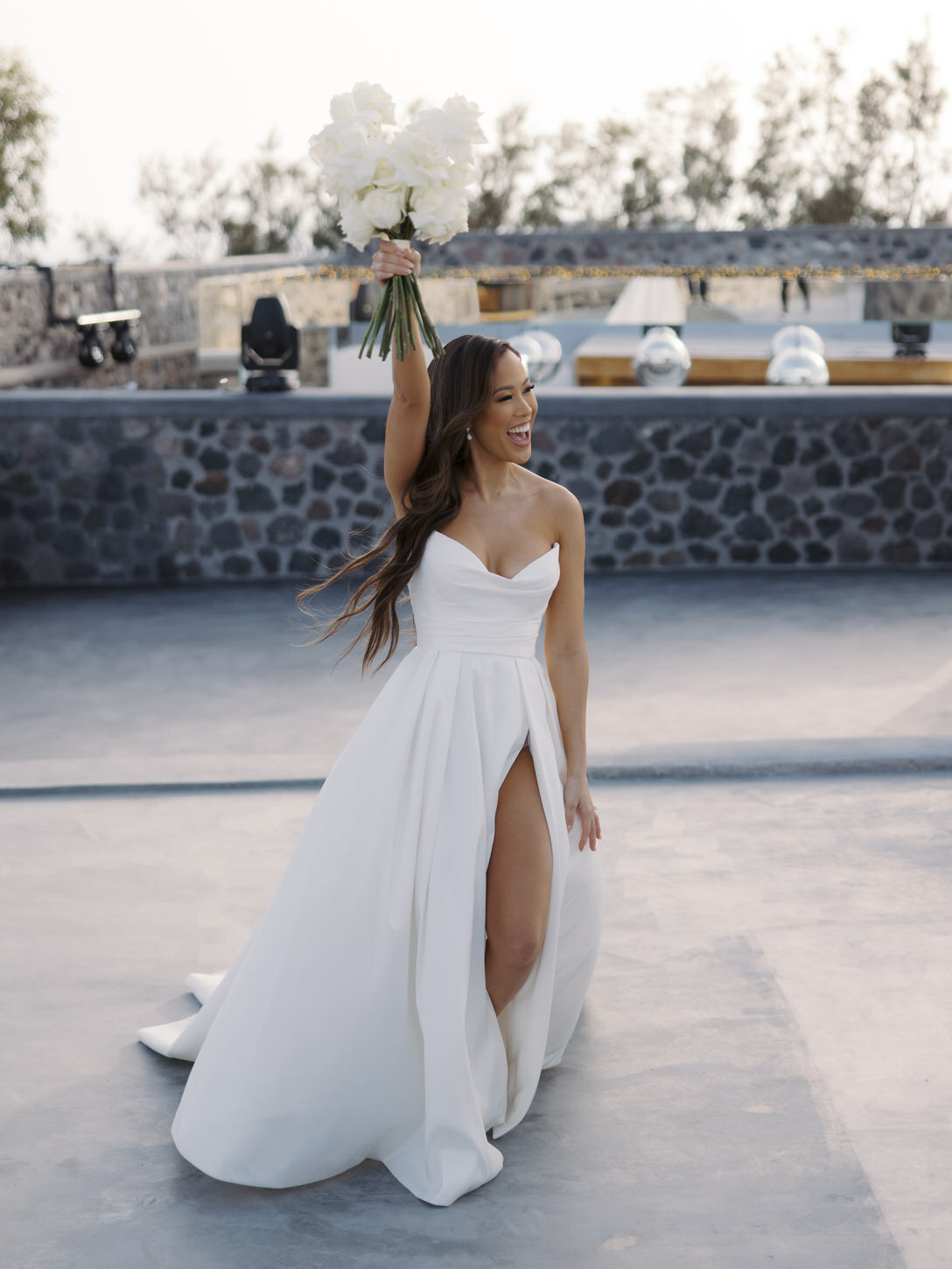 The bride is excitedly holding her white flower bouquet up, captured by destination wedding photographer, Jenny Fu Studio.
