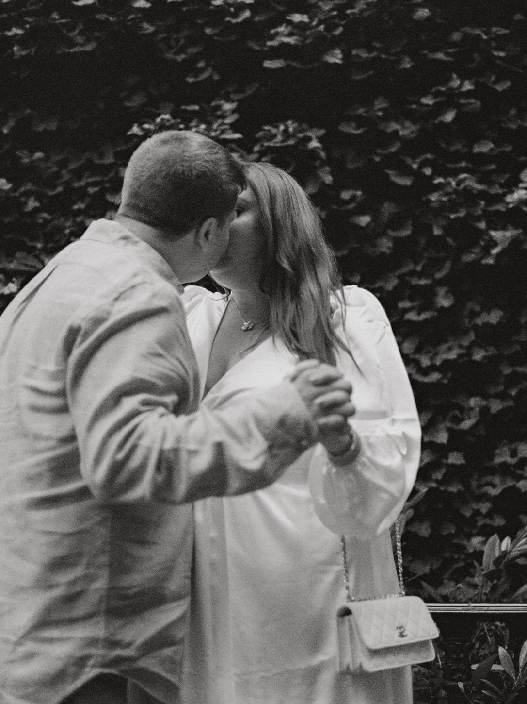 A black and white image of the engaged couple kissing, captured by Jenny Fu Studio in editorial engagement photography.