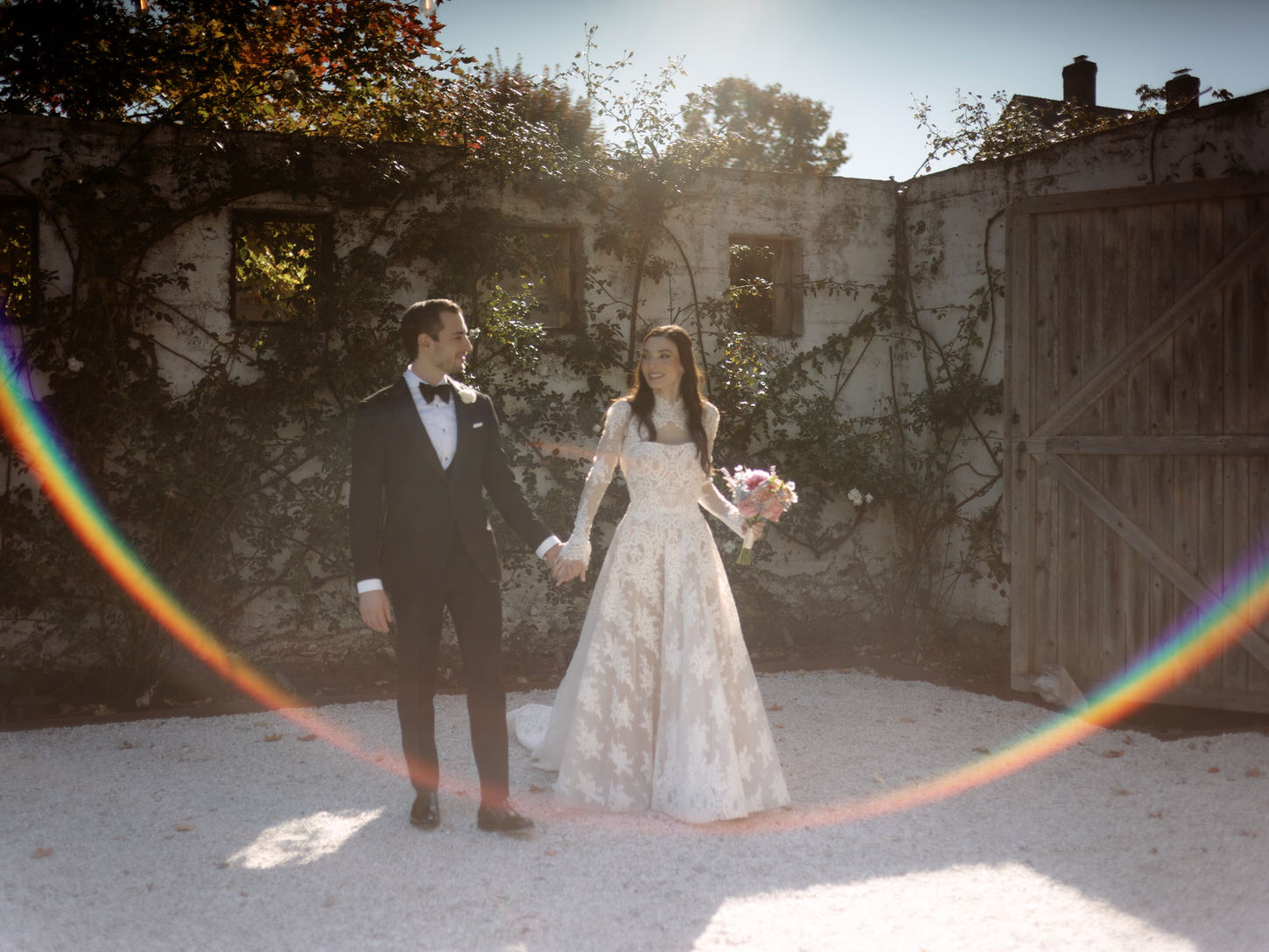 Ethereal wedding moments of the bride and groom walking hand in hand with ivy-covered ruins in the background, captured by Jenny Fu Studio.
