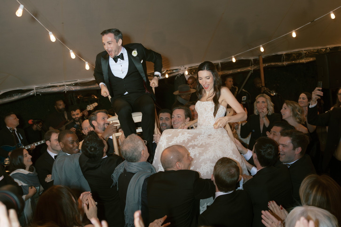 The guests are dancing ecstatically white the newlyweds are lifted up in the Horah.