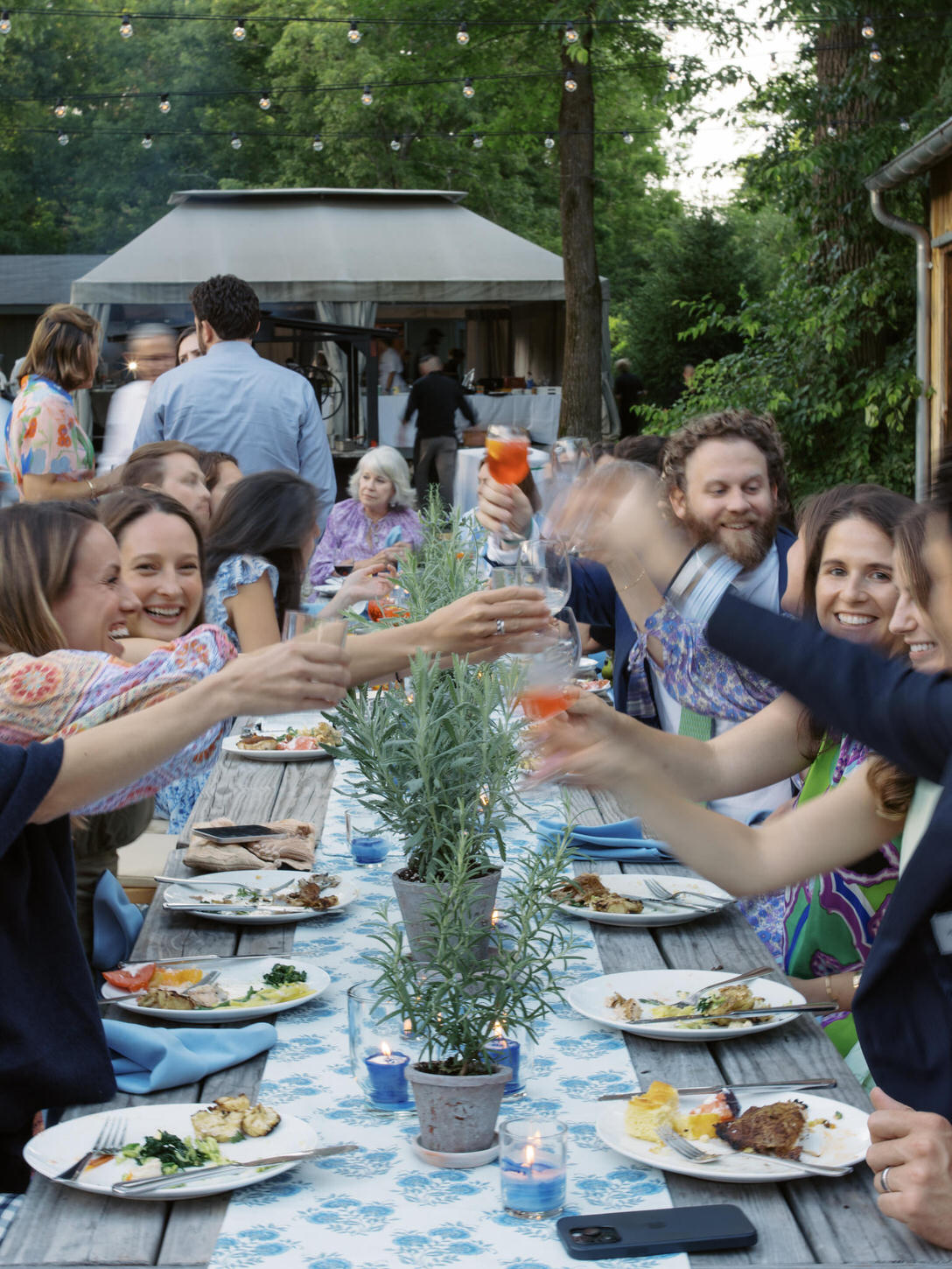 A festive meal shared by the guests at a welcome dinner outdoors in Upstate New York, captured by high-fashion wedding photographer, Jenny fu Studio.