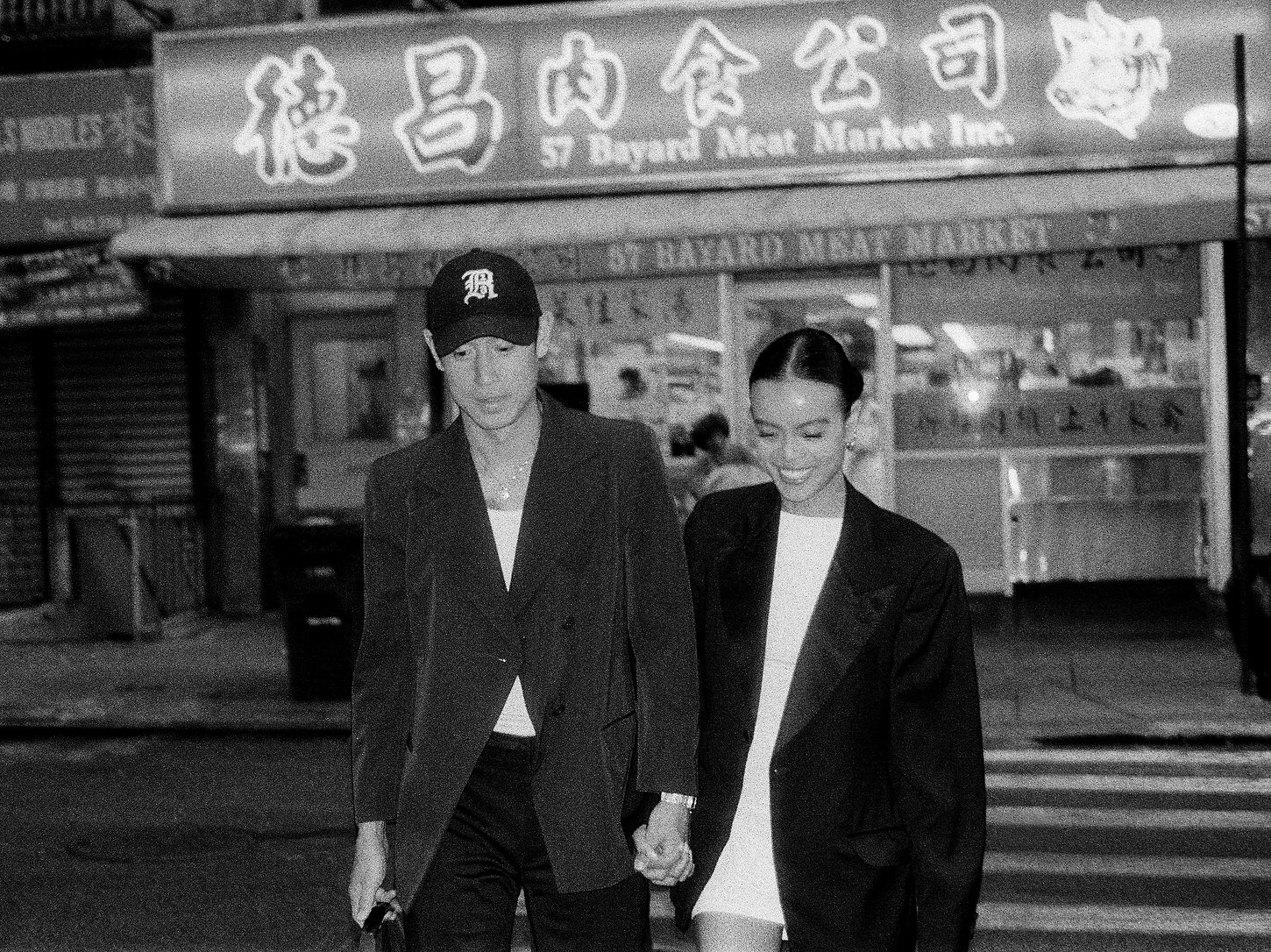 Black and white wedding photo of a couple walking hand in hand through Chinatown NYC.