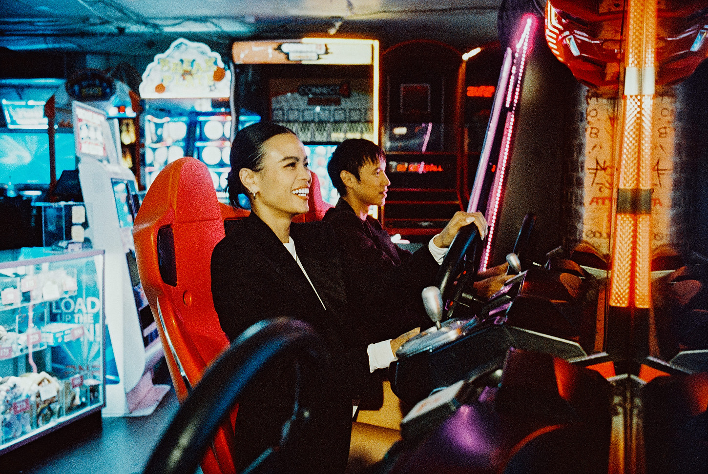 Couple smiling and playing arcade racing games during their wedding shoot in Chinatown.
