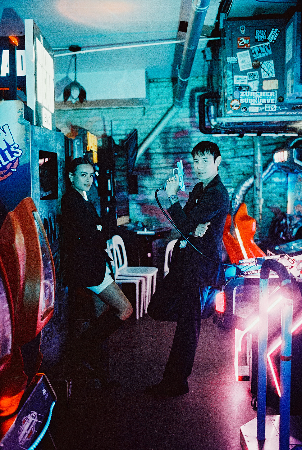 Editorial portrait of a bride and groom posing dramatically inside a neon-lit Chinatown arcade.