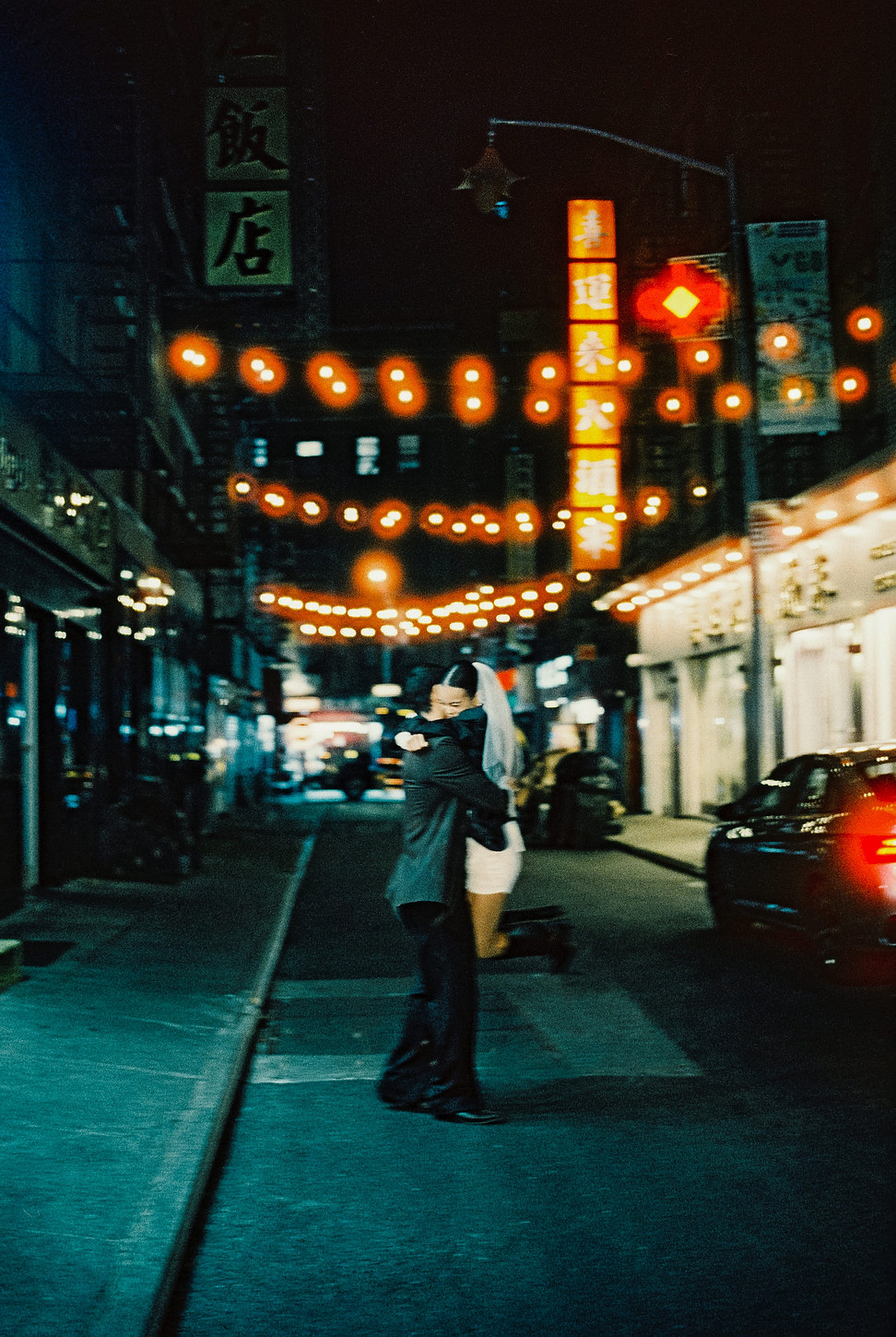 Couple embracing under glowing Chinatown string lights during their NYC elopement.