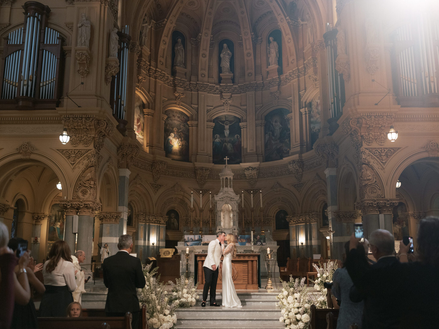Elegant couple share their first kiss as husband and wife inside a grand cathedral in NYC, a timeless wedding photo captured by Jenny Fu Studio.