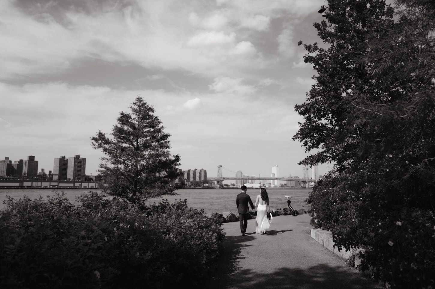 The newlyweds walks intimately hand in hand in a garden overlooking the Brooklyn Bridge in NYC, captured by Jenny Fu Studio.