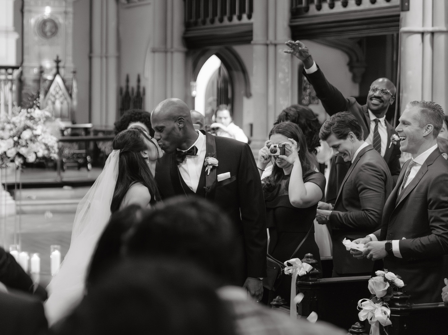 The newlyweds share their first kiss as guests cheer them, Emotional wedding moments captured by Jenny Fu Studio.