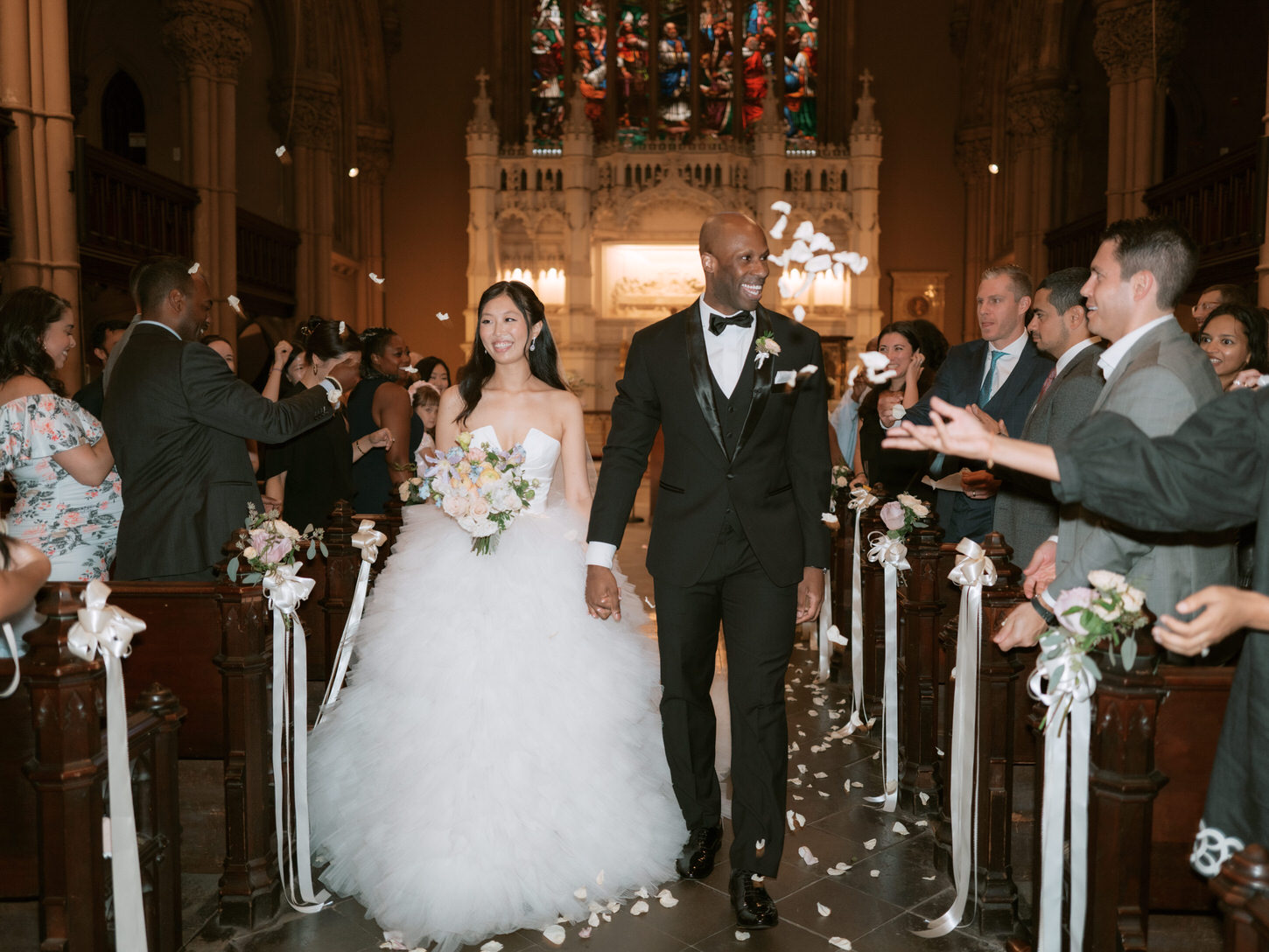 The newlyweds happily walk down the aisle as guests cheer on, captured by Jenny Fu Studio.
