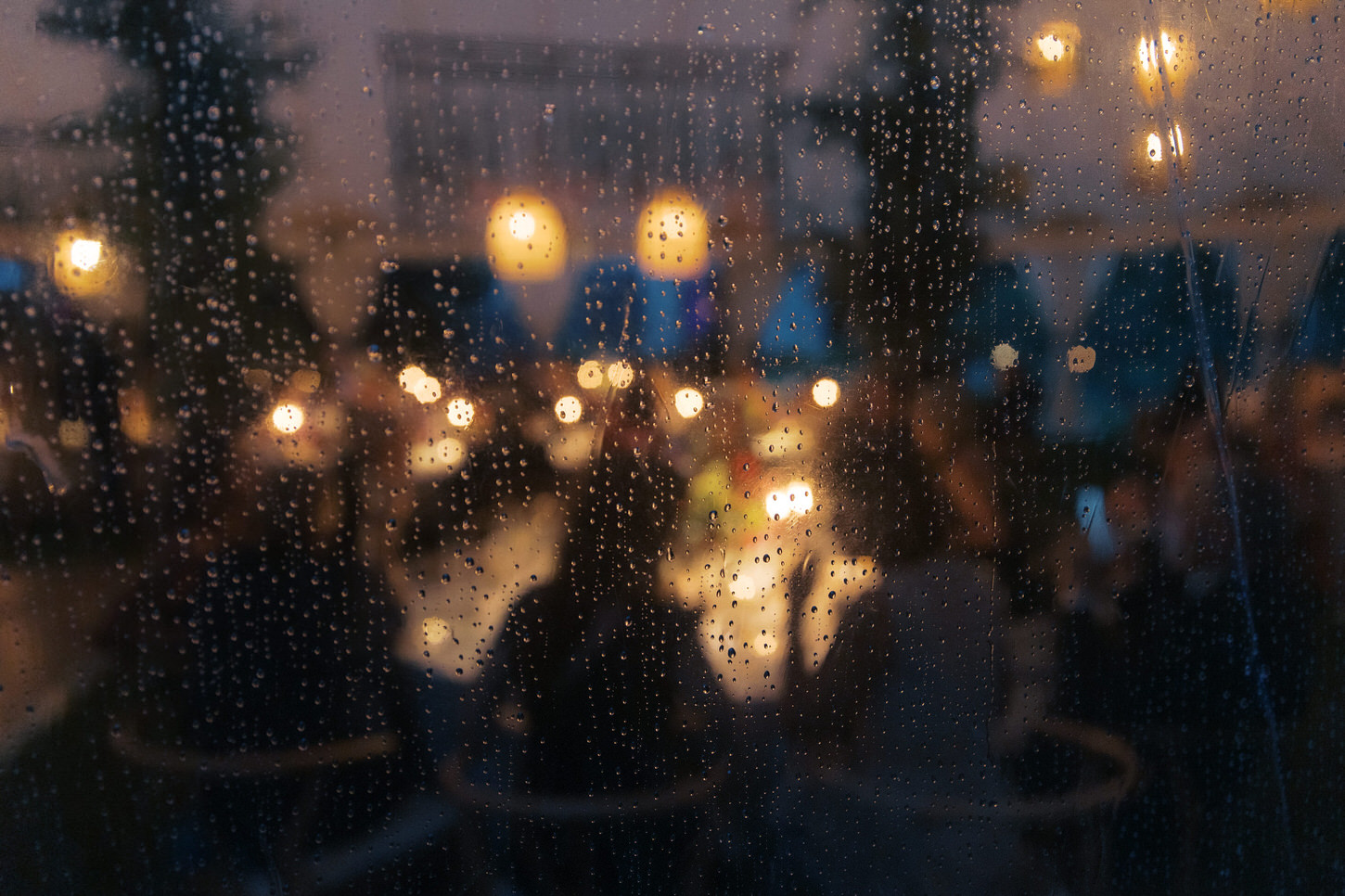 A wedding reception captured from outside of the outdoor tent whilst raining, by Jenny Fu Studio.